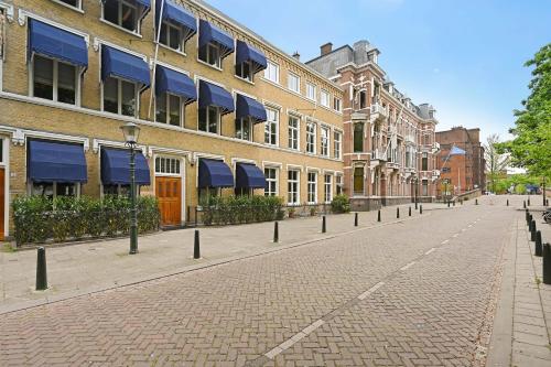 a cobblestone street in front of buildings with blue awnings at novallure nassau residence in The Hague