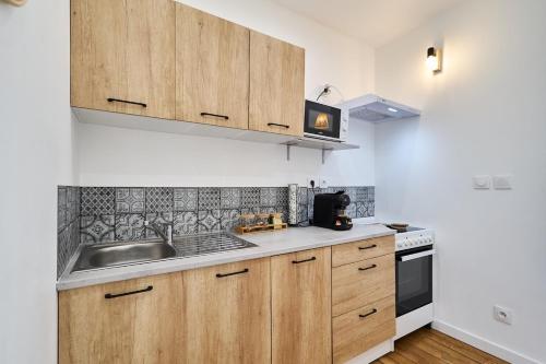 une cuisine avec des armoires en bois et un évier dans l'établissement The Winter, Netflix, Downtown, Quiet & Comfortable, à Reims