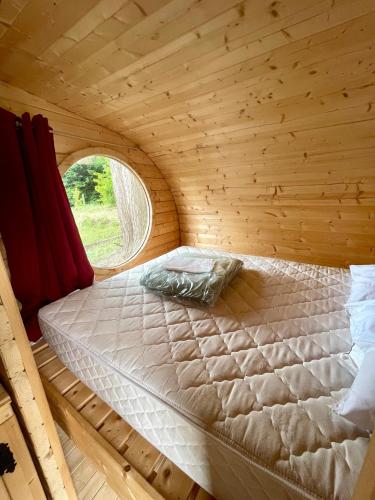Ce lit se trouve dans une chambre en bois dotée d'une fenêtre. dans l'établissement Camping Les Gatinelles, à Bretignolles-sur-Mer