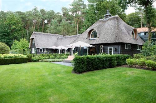 a large house with a thatched roof and a yard at Relais & Chateaux Hotel Landgoed Het Roode Koper in Ermelo