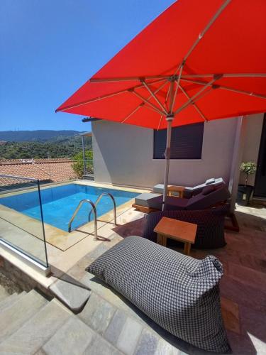 a red umbrella sitting next to a swimming pool at Stavros luxury apartment in Skiathos Town