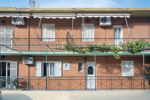 an orange building with white windows and balconies at Rooms Grapevine in Póros Kefalonias