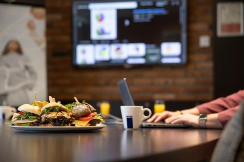 a plate of food on a table with a laptop at Mercure Hotel Zwolle in Zwolle
