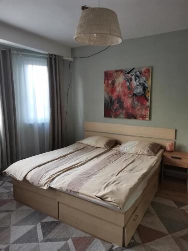 a bed in a bedroom with a painting on the wall at Sólyom Katalin vendégház in Văleni
