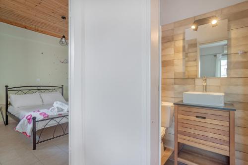 a bedroom with a bed and a sink and a mirror at Rooms Grapevine in Póros Kefalonias