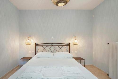 a bedroom with a large white bed with two lamps at Rooms Grapevine in Póros Kefalonias