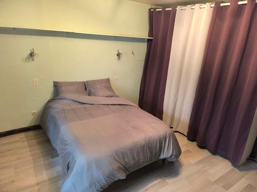 Ce lit se trouve dans une chambre dotée de rideaux violets. dans l'établissement Maison de campagne, à La Motte-en-Beauges