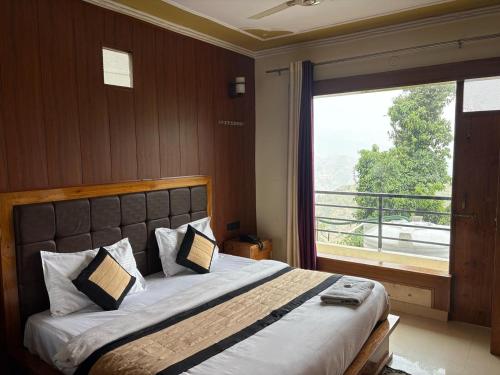 a bedroom with a large bed with a large window at THE Grahil Hotel & Restaurant !Awarded Hotel ! BALCONY ROOMS With BEST Valley View Roof top Cafe ! Near JW Marriott Mussoorie in Mussoorie