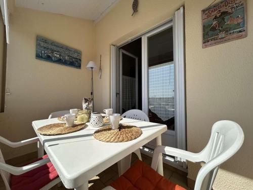 une table blanche et des chaises dans une pièce avec une fenêtre dans l'établissement Studio avec Mezzanine, Balcon et Garage à 200m de la Plage – 4 Couchages - FR-1-224-247, à Saint-Hilaire-de-Riez