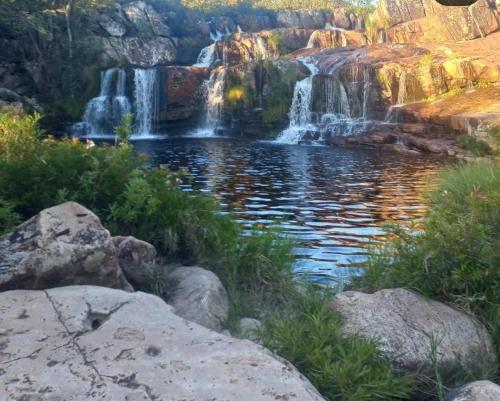 a waterfall in the middle of a pond with rocks at Chalé Bella Serra piscina café da manhã incluso in Jaboticatubas