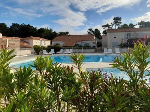 une grande piscine avec des chaises et des arbres dans l'établissement Maison Avec Terrasse, Piscine, Proche Plage et Forêt à Saint-Hilaire-de-Riez ! - FR-1-324A-63, à Saint-Hilaire-de-Riez