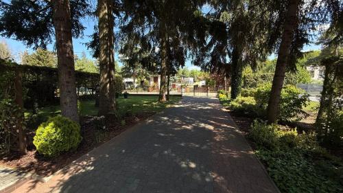 a brick walkway with trees and bushes in a park at Pod Świerkami in Boszkowo