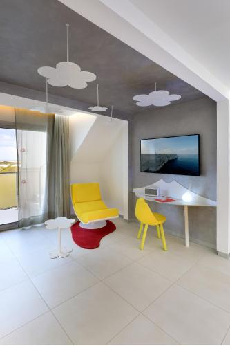 a living room with a yellow chair and a table at Five Flowers Hotel Formentera, member of Melia Collection in Es Pujols