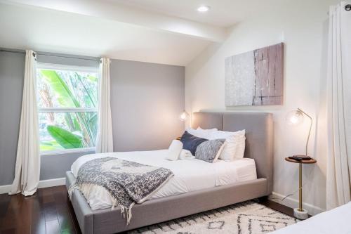 a white bedroom with a bed and a window at Walk to Ventura Boulevard Pool & HotTub with PingPong & BBQ in Sherman Oaks
