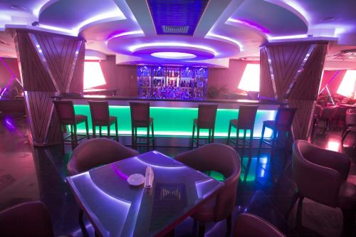 a bar in a restaurant with purple and green lighting at Hotel 71 in Dhaka