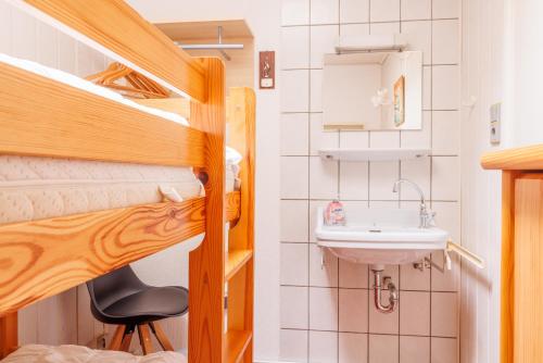 Habitación pequeña con litera y lavamanos en Jan Roepespad 11, en Hollum