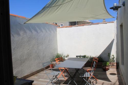 - une table et des chaises sur une terrasse avec un parasol dans l'établissement The Little Terrace, à Saint-Martin-de-Ré