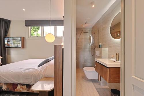 a bedroom with a bed and a sink and a bathroom at novallure nassau residence in The Hague