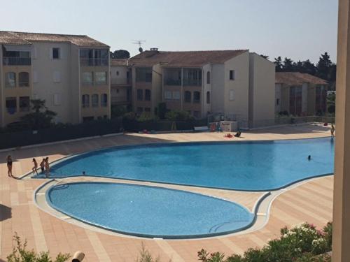 une grande piscine devant certains bâtiments dans l'établissement Un cocon aux marquises - Joli T2 Dégagée Sud- ouest Piscine Tennis, à Fréjus