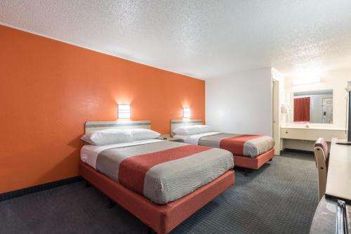 two beds in a room with orange walls at Travelodge by Wyndham Lansing in Lansing