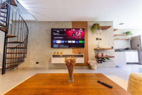 a living room with a table and a tv on the wall at Star Green 211 - Triplex com linda vista e ótima localização in Campos do Jordão