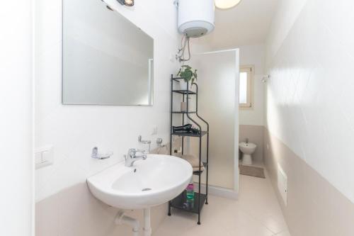 a white bathroom with a sink and a mirror at Alba Azzurra in San Pasquale