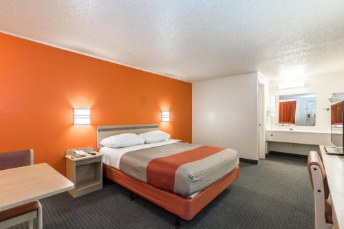una camera d'albergo con letto a parete arancione di Travelodge by Wyndham Lansing a Lansing