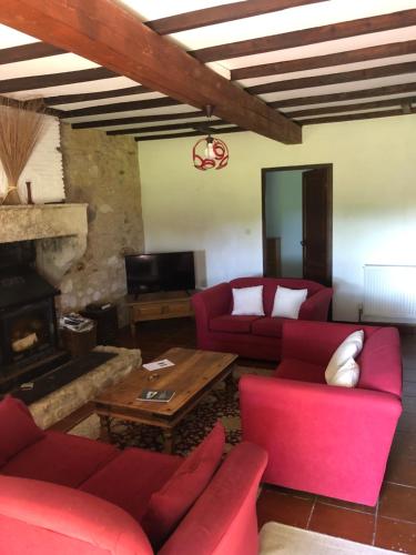 - un salon avec des canapés rouges et une cheminée dans l'établissement Rose cottage, à Montcaret