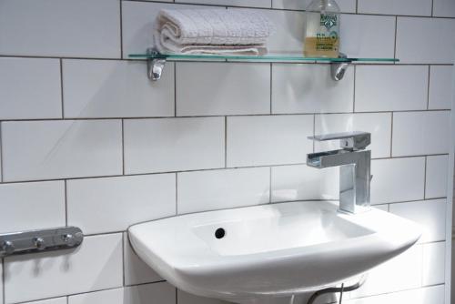 - une salle de bains blanche pourvue d'un lavabo et d'une étagère dans l'établissement Koselig leilighet i Antibes, à Antibes