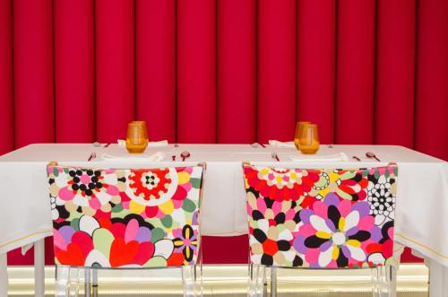 a table with two chairs in front of a red curtain at Five Flowers Hotel Formentera, member of Melia Collection in Es Pujols