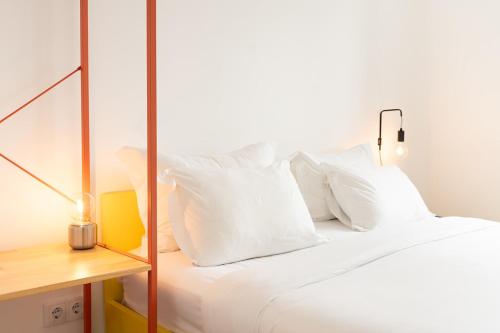 a bedroom with a white bed with white pillows at SATURdAYS in Lisbon