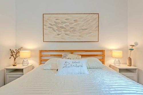 a bedroom with a white bed with two lamps at Les Terrasses de la Palud in Landéda
