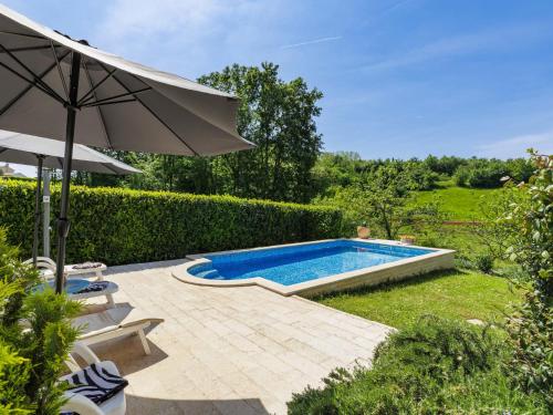 a swimming pool in a yard with an umbrella at Holiday Home Palma by Interhome in Karojba