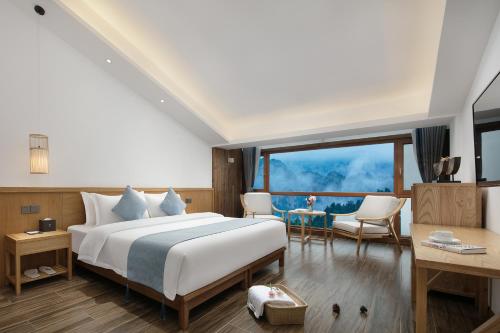 a bedroom with a large bed and a table and chairs at Hilltop House Resort in Zhangjiajie
