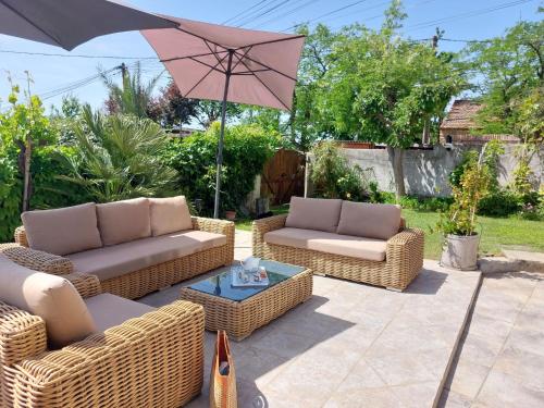 une terrasse avec 3 chaises en osier et un parasol dans l'établissement Apartment La Bastide Neuve by Interhome, à Saint-Cyr-sur-Mer