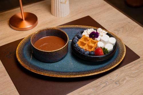 a plate of food with waffles and a bowl of sauce at Le Saint Georges in Gruyères
