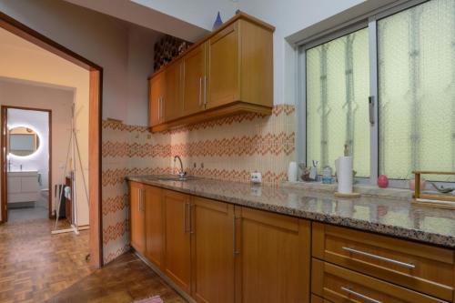 a kitchen with wooden cabinets and a large window at Casa de Férias T2_Frente de praia in São Martinho do Porto