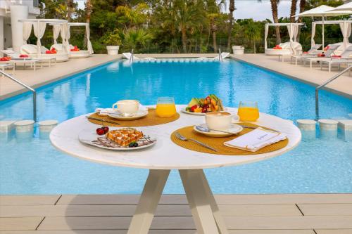 a table with food and drinks next to a swimming pool at Five Flowers Hotel Formentera, member of Melia Collection in Es Pujols