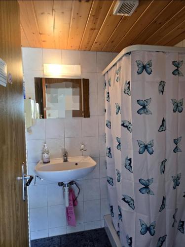 a bathroom with a sink and a shower curtain with butterflies at Doppelzimmer direkt vorm Emmental in Eriswil