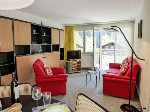 uma sala de estar com duas cadeiras vermelhas e uma mesa em Apartment Chalet Wyssefluh by Interhome em Grindelwald