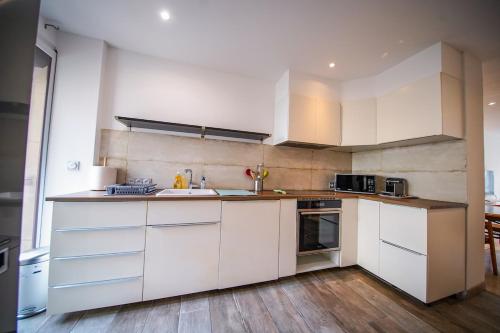 une cuisine avec des armoires blanches et un évier dans l'établissement Stylish apartment in the center of Avignon, à Avignon