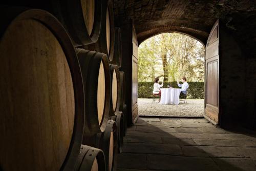 two people sitting at a table with wine barrels at Agriturismo Il Pozzo in Greve in Chianti
