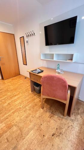 a desk with a chair and a television on a wall at Hotel zur Loreley - Garni in Sankt Goar
