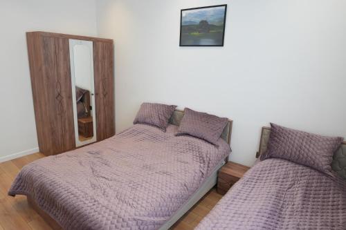 a bedroom with a bed with purple comforter and a mirror at White Harmony Houses in Şamaxı