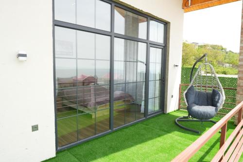 a screened porch with green grass and a swing at White Harmony Houses in Şamaxı