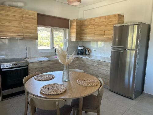 una cucina con tavolo e frigorifero in acciaio inox di Saint George family house a Palaia Fokaia