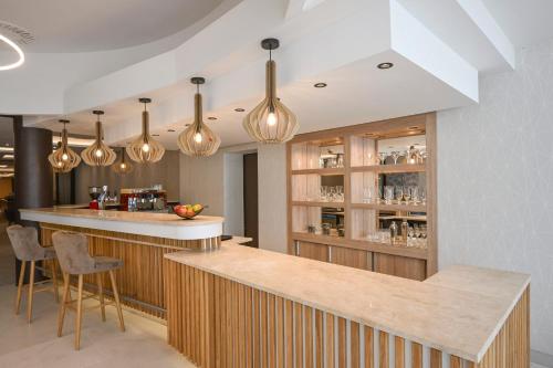 a kitchen with a bar with lights at AquaMed Hotel Harkány in Harkány