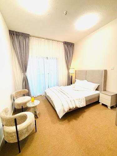 a bedroom with a large bed and a chair at La Pearl Vacation Home in Ajman 