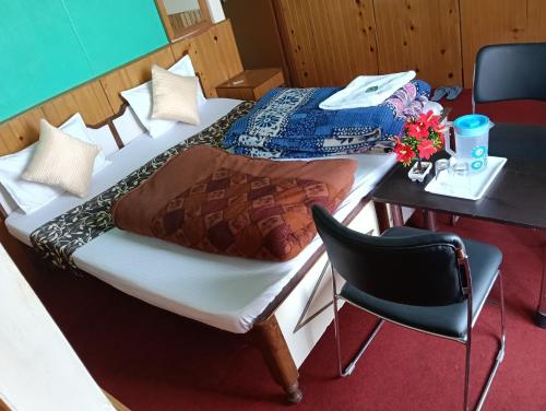 a bedroom with two beds and a table and a chair at Monal Inn in Mīlam