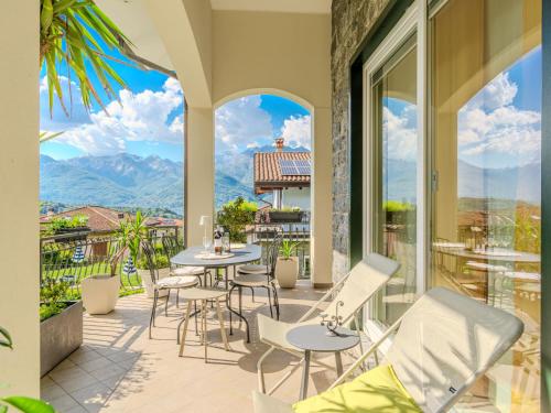 d'une terrasse avec des tables et des chaises sur un balcon avec des montagnes. dans l'établissement Holiday Home Aurora by Interhome, à Colico
